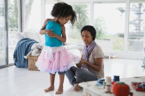 Mother repairing young daughter's dance skirt.