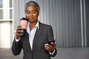 Businesswoman holding coffee and texting