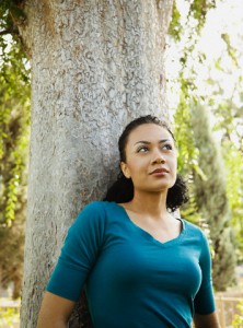 African American woman leaning against tree