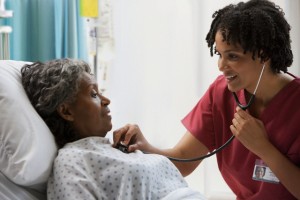 African American nurse using stethoscope on hospital patient
