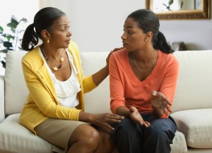 Mother and daughter talking on sofa