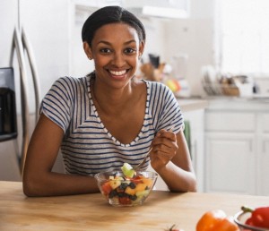 Mixed race woman eating fruit salad in kitchen