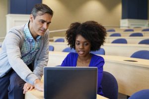 Young woman with teacher in lecture hall