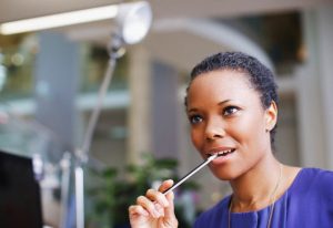 Pensive businesswoman biting end of pencil in office